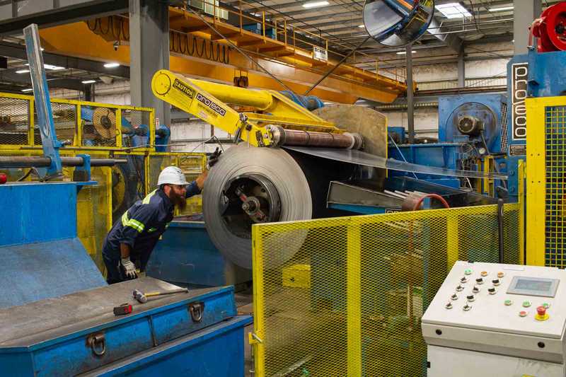 Worker monitoring a slitting machine at Oregon Metal Services