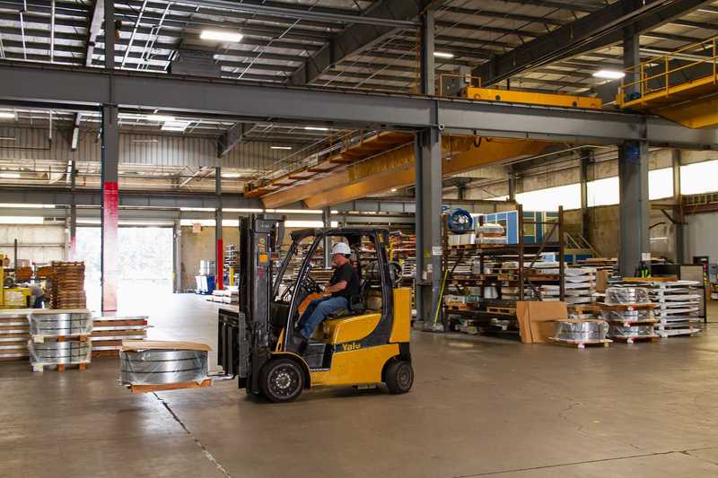 Worker driving a fork lift on the shop floor at Oregon Metal Services