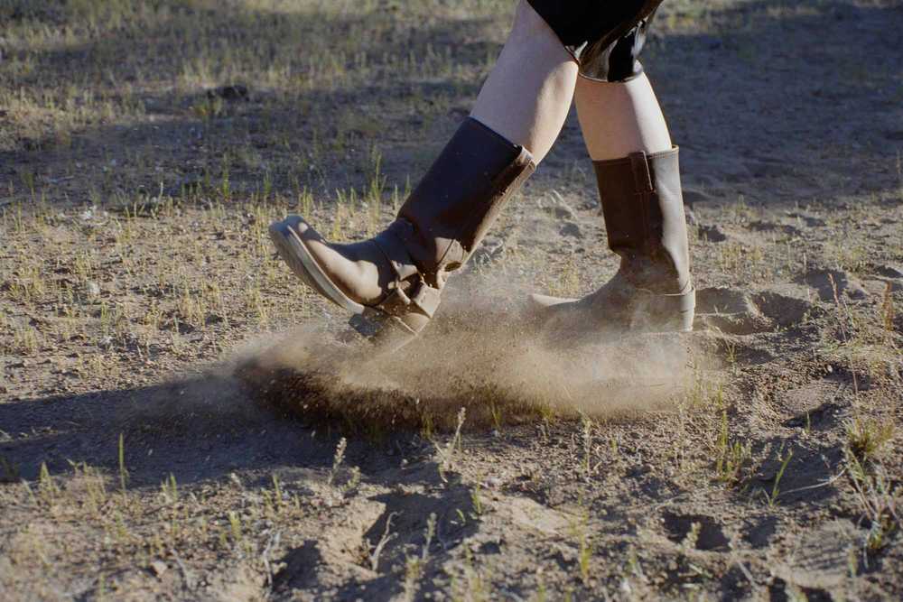 film photography of cowboy boots kicking dirt